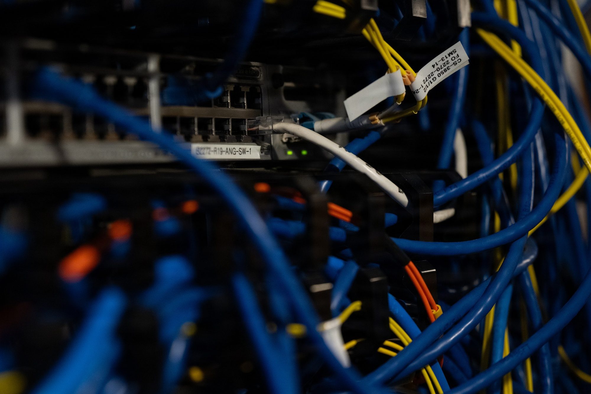 Blue and yellow network cables plugged into a labelled switch in a server rack